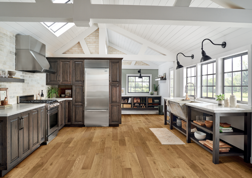 warm tone hardwood flooring in kitchen with dark cabinetry